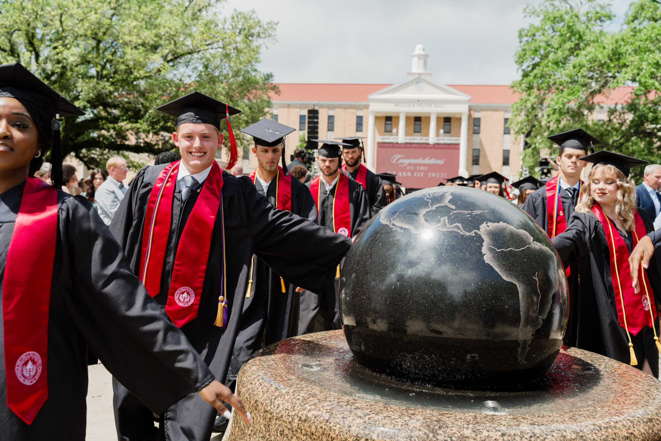 globe statue and graduates